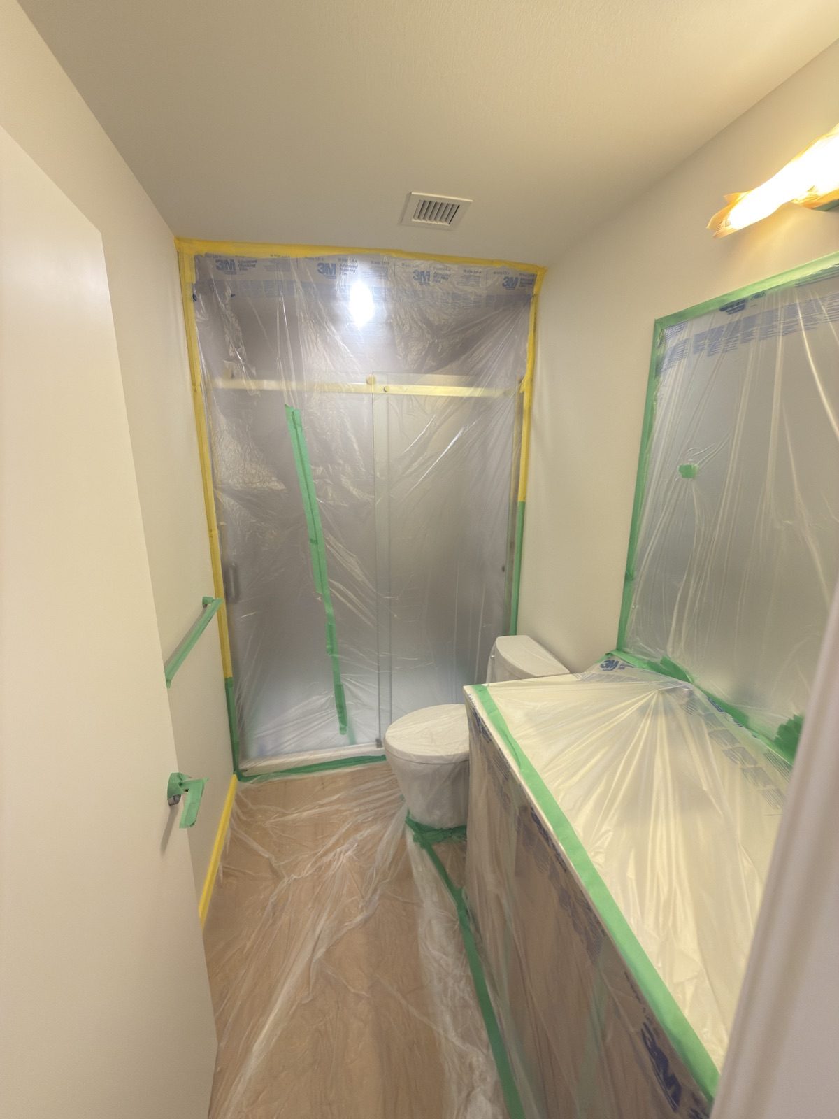 Bathroom with shower glass, toilet and vanity masked in plastic